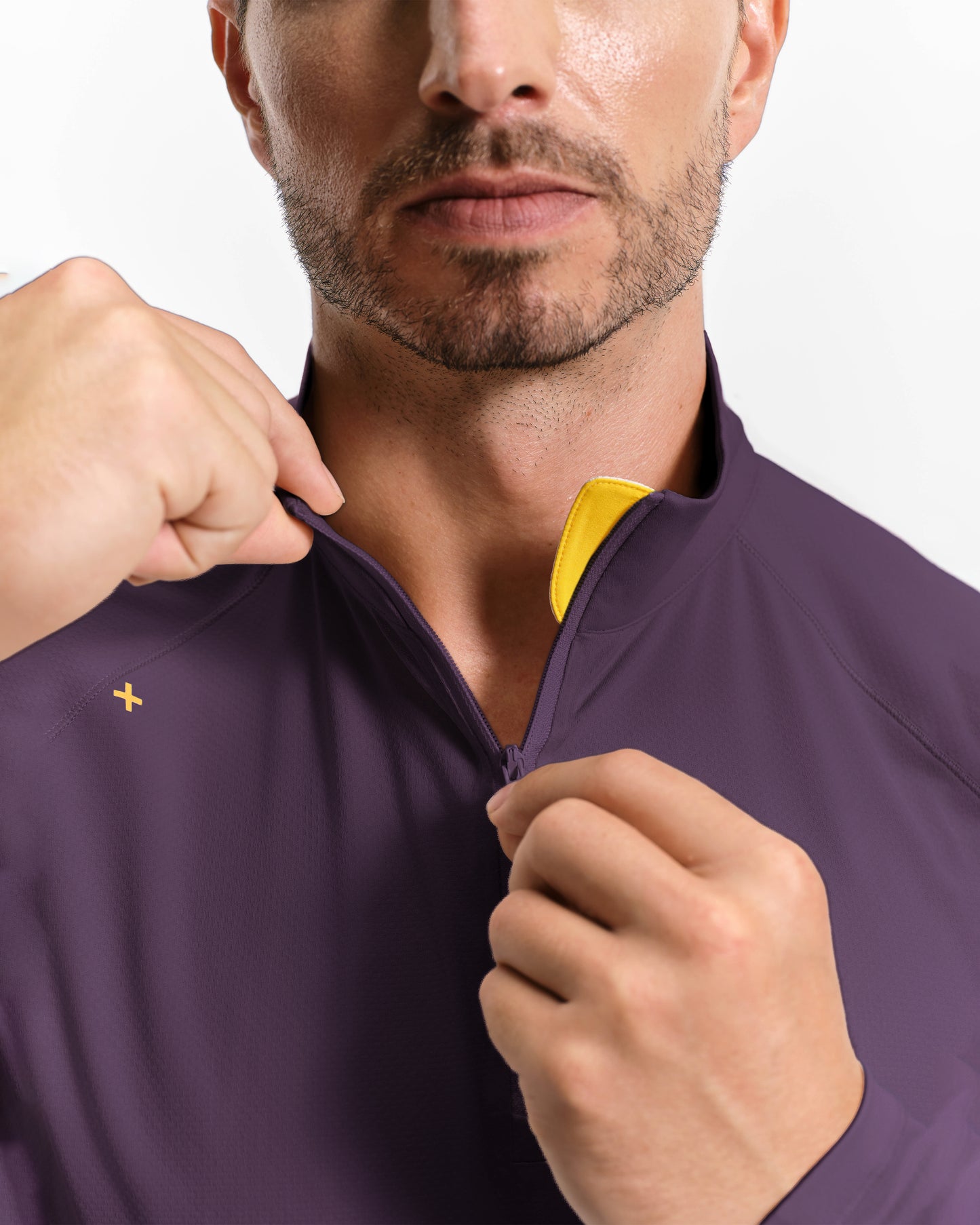Man wearing a purple jacket with a yellow zipper detail, adjusting the collar.